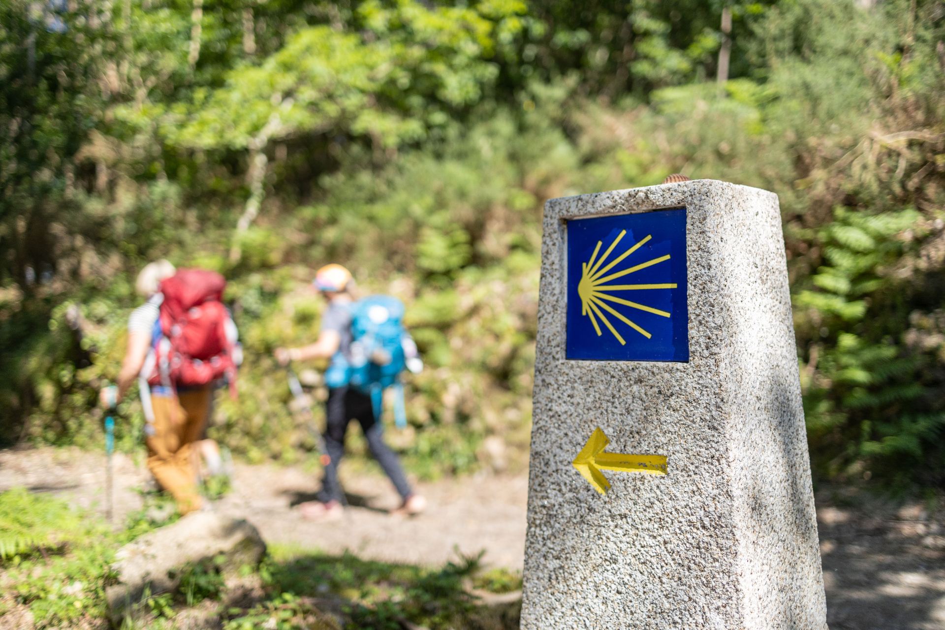 Mojón del Camino de Santiago con peregrino caminando hacia Fisterra y Muxía en Galicia